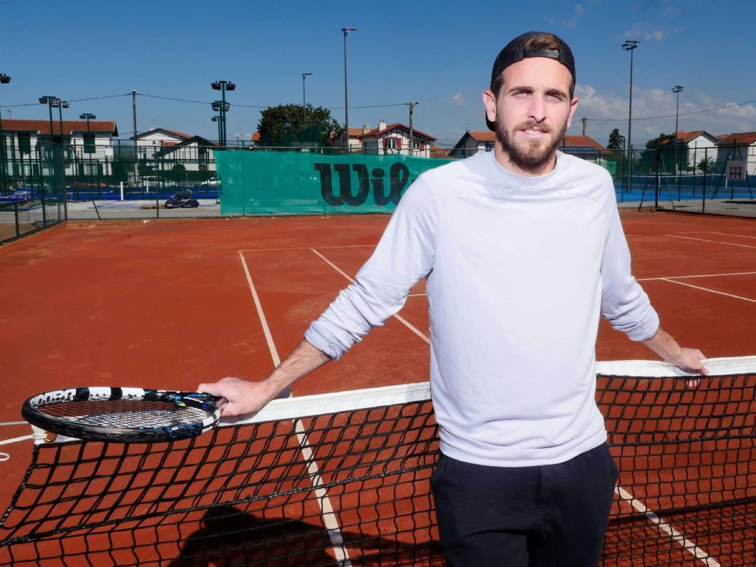 Alexis Musialek sur un court en terre battue, raquette à la main